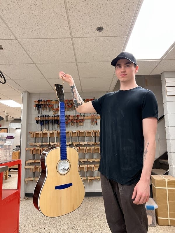 A student holds a guitar he has built
