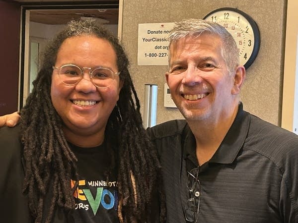 Two people stand together in a broadcast studio