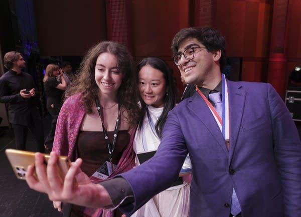 A pianist takes a selfie with two other people