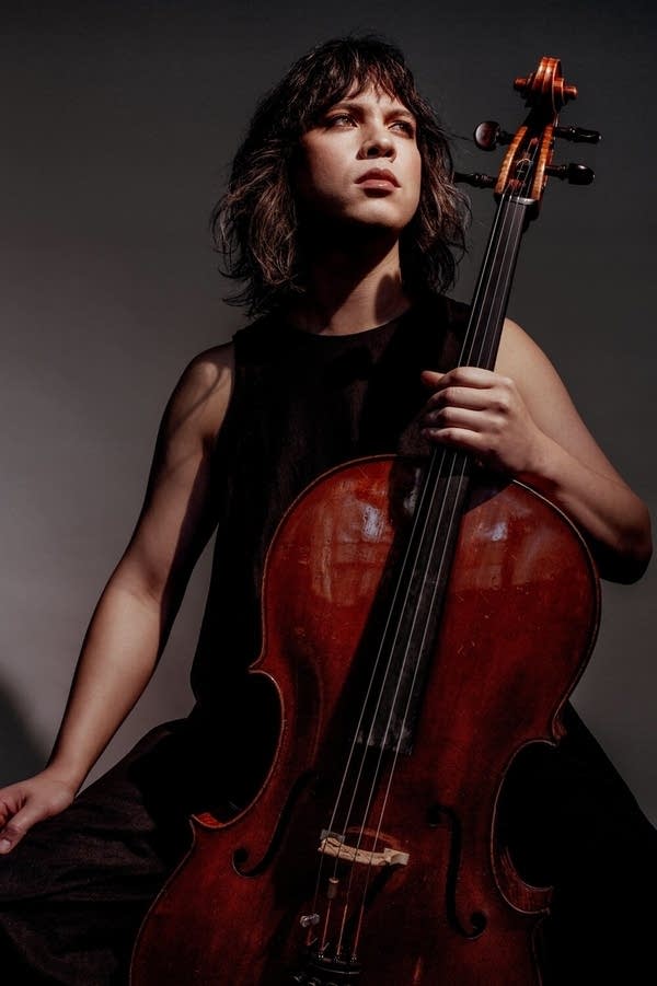 A musician poses for a portrait while holding a cello